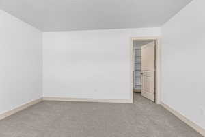 Unfurnished room featuring light carpet and baseboards