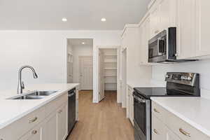Kitchen featuring stainless steel appliances, light wood finished floors, light stone countertops, recessed lighting, and white cabinets