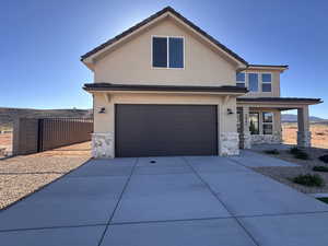 View of front facade featuring stone siding, stucco siding, concrete driveway, an attached garage, and covered porch