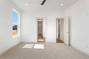 Unfurnished bedroom featuring a spacious closet, light colored carpet, recessed lighting, and ceiling fan