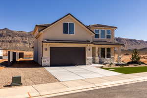 View of front of home with a mountain view, stone siding, driveway, stucco siding, and covered porch