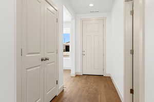 Hallway with light wood-style flooring and recessed lighting