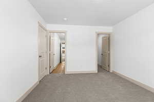 Unfurnished bedroom with light carpet and baseboards