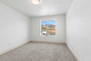 Unfurnished room featuring light carpet and baseboards