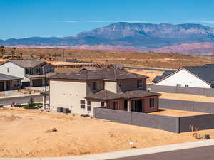 Back of property with stucco siding, a fenced backyard, a mountain view, and a residential view