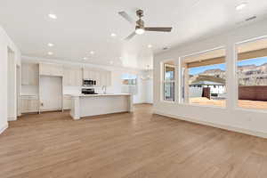 Unfurnished living room featuring a ceiling fan, light wood-type flooring, a chandelier, and a mountain view