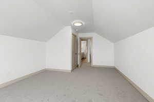 Bonus room featuring light colored carpet and lofted ceiling