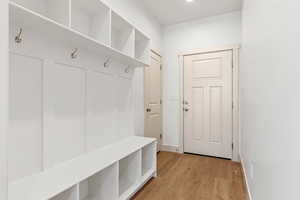 Mudroom featuring light wood finished floors and baseboards