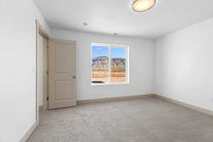 Spare room featuring a mountain view and light carpet