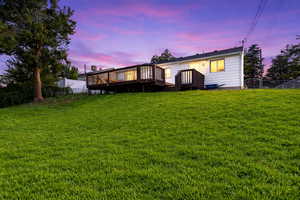 Back of property at dusk featuring a fenced backyard and a wooden deck