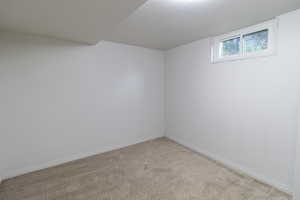 Empty room with light colored carpet and baseboards