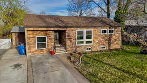 Bungalow-style house with roof with shingles, a front yard, stone siding, and a garage