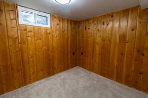 Carpeted empty room with a textured ceiling and wood walls