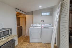 Laundry room featuring washing machine and clothes dryer and stone finish flooring