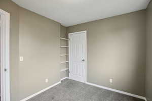 Unfurnished bedroom featuring baseboards and dark carpet