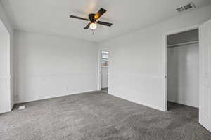 Unfurnished bedroom featuring dark carpet, ceiling fan, and a closet