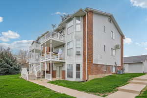 View of property exterior featuring a yard, brick siding, and a balcony