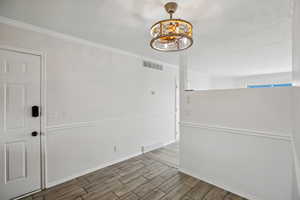 Spare room with wood finish floors, crown molding, and a textured ceiling