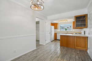 Kitchen with light countertops, a peninsula, wood finish cabinetry, glass fronted cabinets, and wood tiled floors