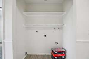 Laundry area with hookup for a washing machine, electric dryer hookup, wood finished floors, and hookup for a gas dryer