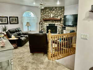 Carpeted living room featuring a fireplace and a ceiling fan