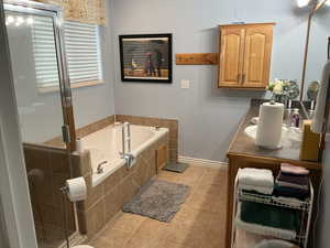 Bathroom with double vanity, light tile patterned floors, a bath, and a stall shower