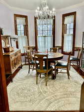 Dining room with ornamental molding, hanging lights, wood finished floors, and healthy amount of natural light