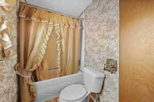 Full bath featuring toilet and shower / bathtub combination with curtain