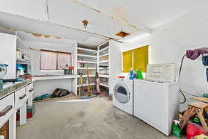 Laundry area featuring concrete flooring, washing machine and dryer, and a workshop area