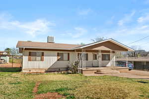Rear view of property featuring covered porch, roof with shingles, crawl space, and a lawn
