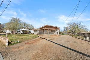 View of front facade with covered porch and dirt driveway