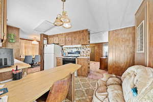 Kitchen featuring wooden walls, gas range, freestanding refrigerator, hanging light fixtures, and light countertops