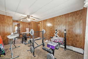 Workout room with wooden walls, carpet floors, and a ceiling fan