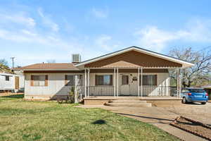 View of front of property featuring a porch, a shingled roof, and a front yard