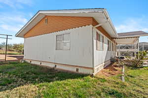 View of side of property with a lawn and crawl space