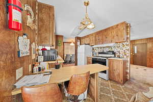 Kitchen featuring light countertops, a peninsula, white appliances, decorative light fixtures, and a kitchen breakfast bar