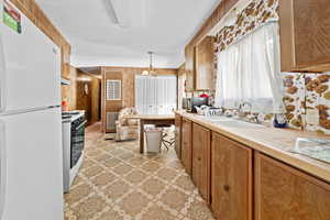 Kitchen featuring white appliances, light countertops, wood finish cabinets, wooden walls, and hanging lights