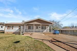 View of front of house with covered porch, a front yard, and crawl space