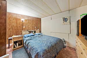 Bedroom featuring wooden walls and vaulted ceiling