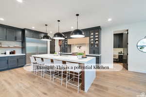 Two tone kitchen with light wood-style flooring, a spacious island, decorative light fixtures, light stone countertops, and glass insert cabinets