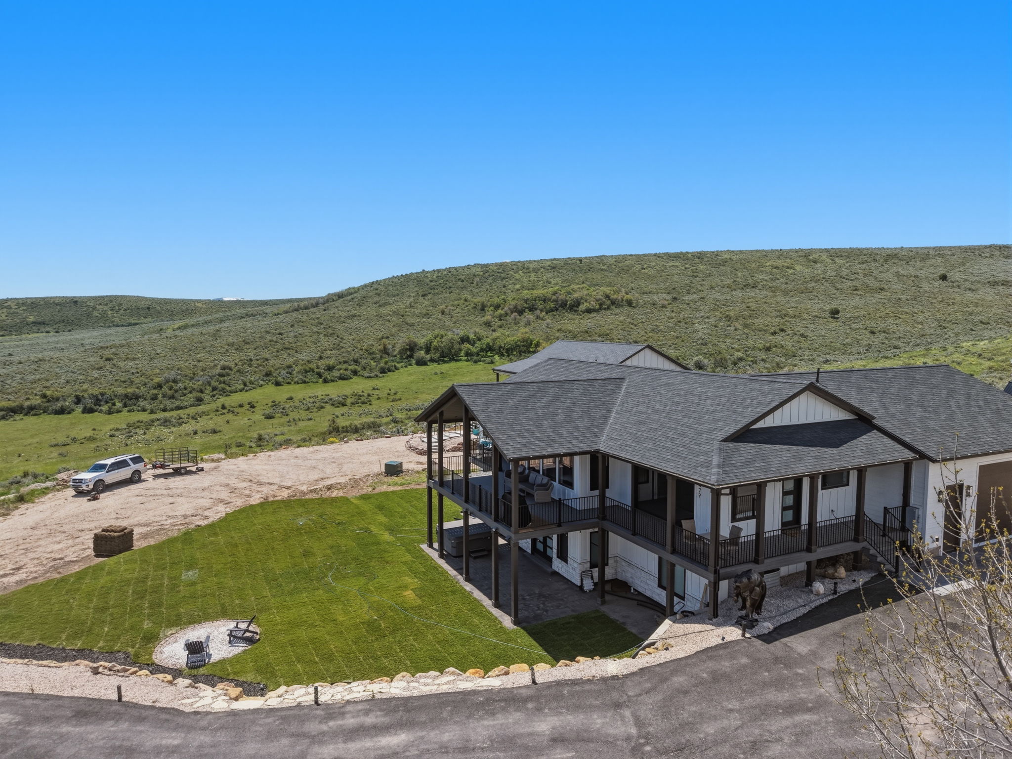 Multi-level residence featuring a dark asphalt shingle roof, white siding, and dark trim