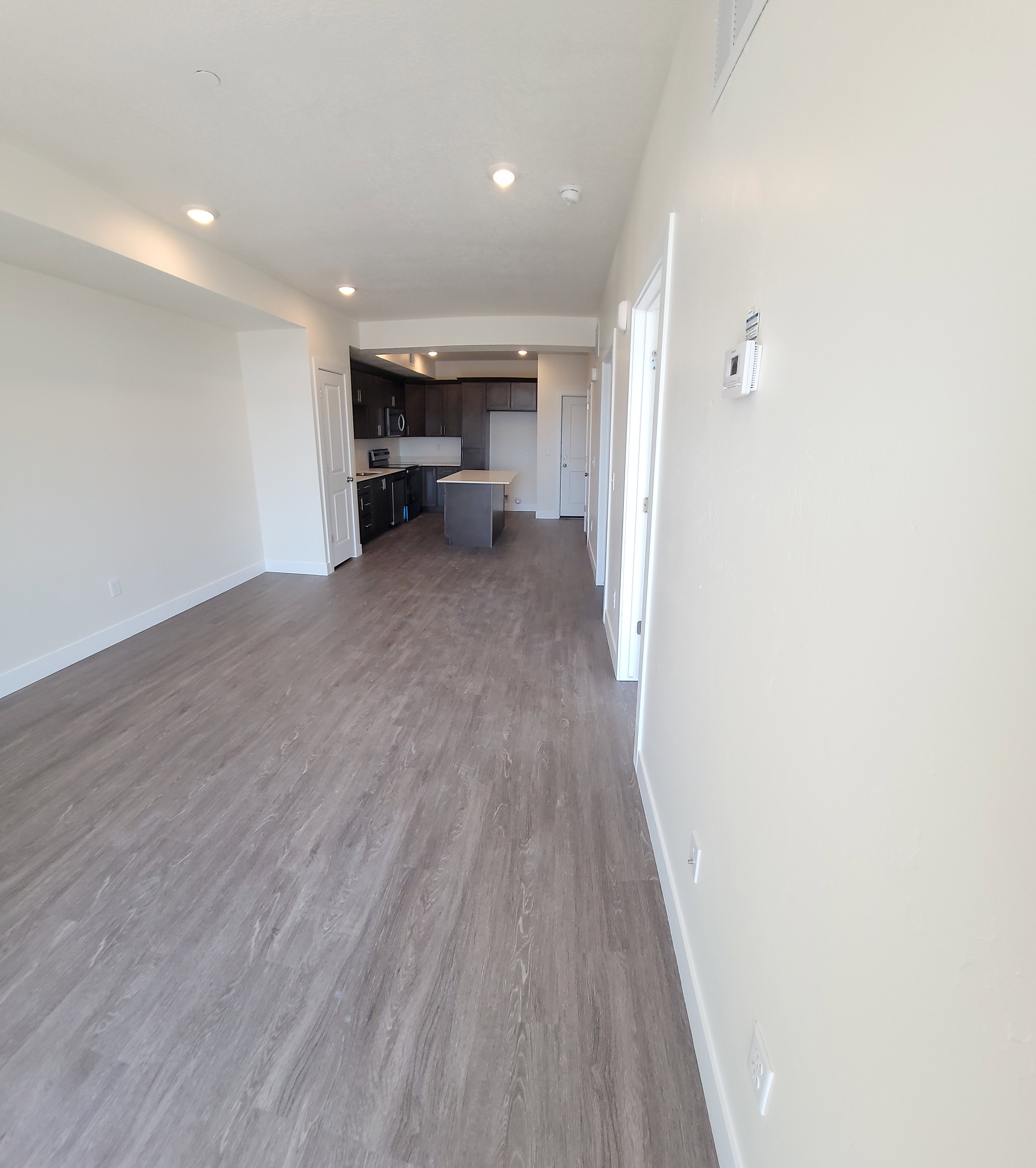 Unfurnished living room featuring dark wood-type flooring and recessed lighting