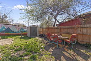 Fenced backyard with outdoor dining area and a storage shed