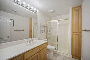 Bathroom with vanity, a stall shower, light tile patterned floors, and a textured ceiling