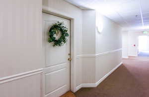 Corridor featuring dark carpet and a drop ceiling