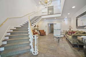 Living area featuring crown molding, a high ceiling, and a chandelier