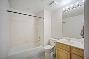 Full bathroom with vanity, light tile patterned floors, shower / bath combination, and a textured ceiling