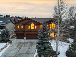 Chalet / cabin featuring an attached garage, driveway, stone siding, and board and batten siding