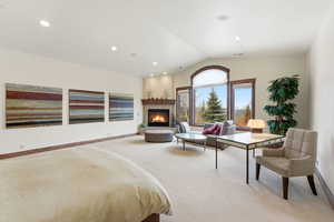 Bedroom featuring light colored carpet, a lit fireplace, and recessed lighting