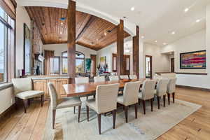 Dining room with light wood-style flooring and a high wooden beamed ceiling